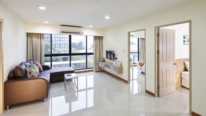 Een moderne woonkamer met een bank, een salontafel en een televisie. Er is een balkon zichtbaar door het raam.