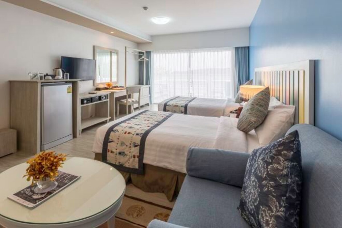 A hotel room with a bed, a sofa, a desk, and a television.