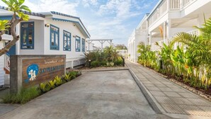 A hotel entrance with a signboard, a concrete pathway, and a row of plants. - Somewhere Koh Sichang (Ko Sichang)