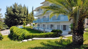 A multi-story hotel with balconies, surrounded by greenery and palm trees. - Roditsa Patritsia Apartments (Kassandra)