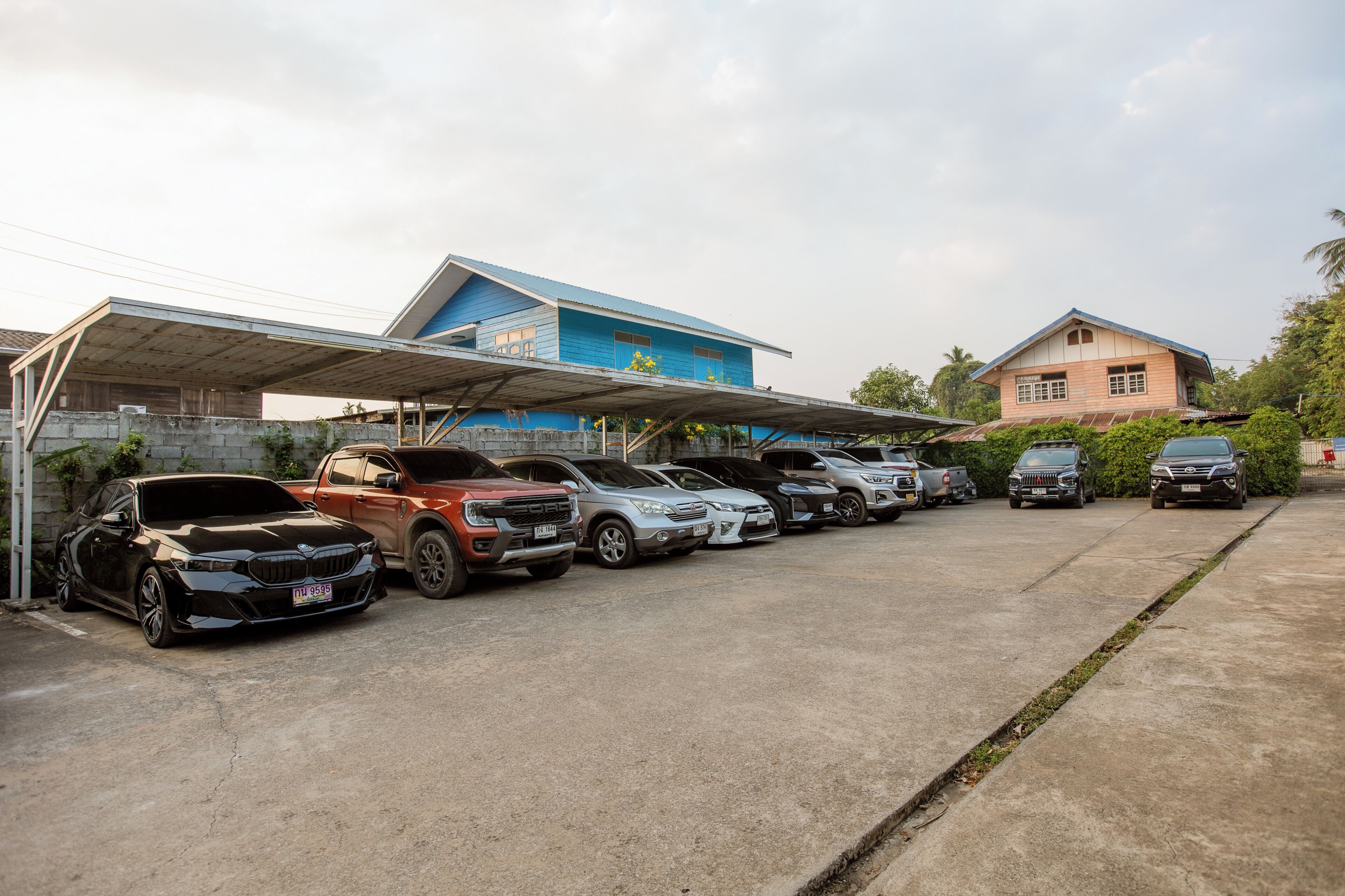 A parking lot with multiple cars and a building with a blue roof.