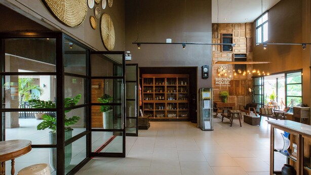 Un interior moderno con puerta de cristal, una estantería de madera y una zona de estar con mesas y sillas.