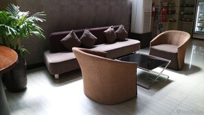A modern lounge area with a sofa, two armchairs, a glass-top coffee table, and a potted plant. - GT Hotel Iloilo (Iloilo)
