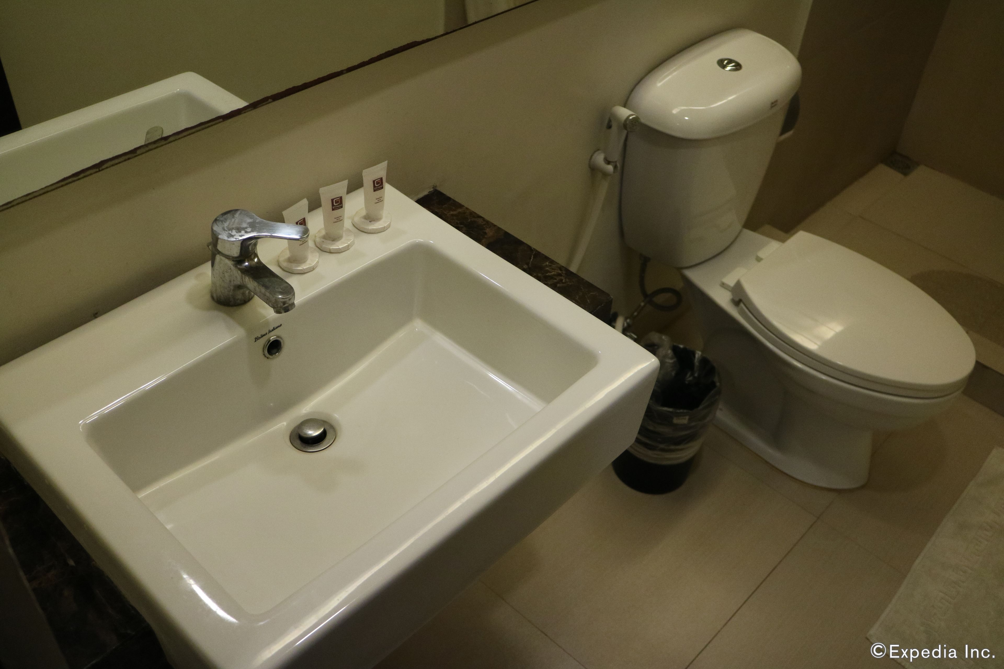A bathroom with a white sink, a toilet, and a hand soap dispenser.