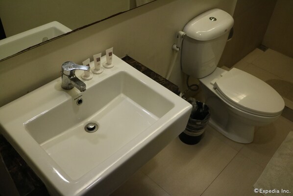 A bathroom with a white sink, a toilet, and a hand soap dispenser. - GT Hotel Iloilo (Iloilo)