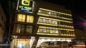 A hotel with a prominent 'GT Hotel' sign, multiple floors, and a parking area with vehicles. - GT Hotel Iloilo (Iloilo)