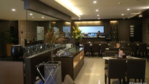 A modern restaurant with a bar area, seating, and a large screen displaying a person. - GT Hotel Iloilo (Iloilo)
