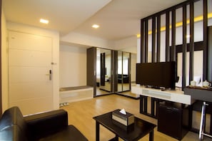 A modern living room with a sofa, a coffee table, a TV, and a mirrored wardrobe. - Hotel Accord (Yangon)