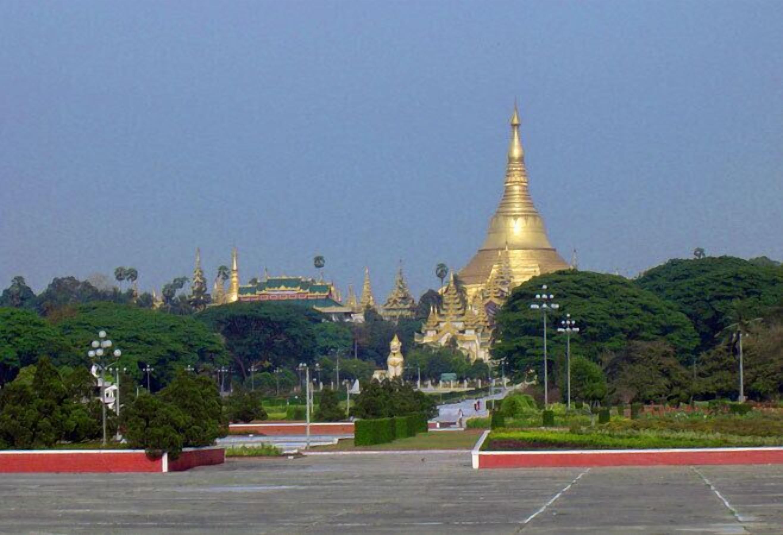 A large golden stupa surrounded by lush greenery and smaller pagodas.