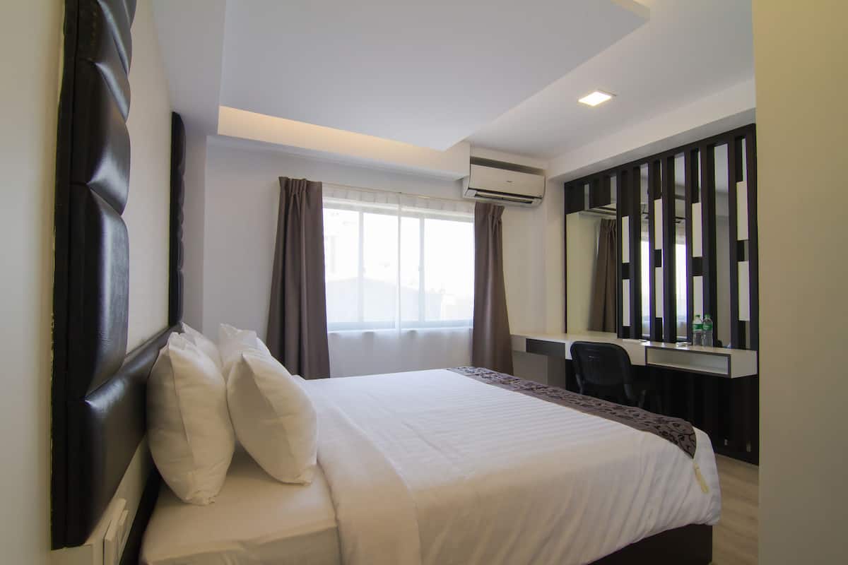 A hotel room with a large bed, a desk, and a mirror.