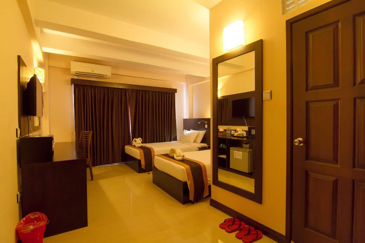 A hotel room with a bed, a desk, a mirror, and a door.