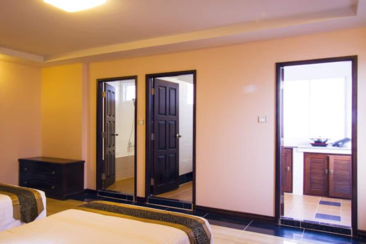 A hotel room with two beds, a dresser, a mirror, and a door leading to a balcony.