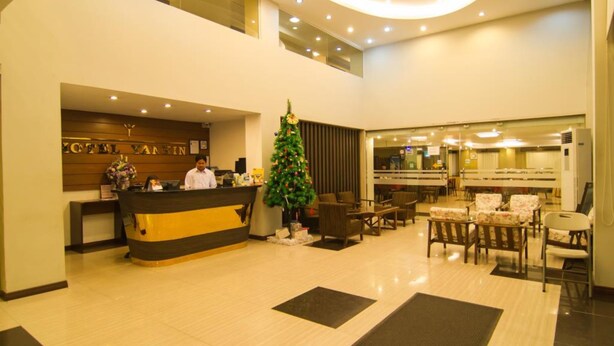Un hall de hotel con una mesa de recepción, un árbol de Navidad y una zona de estar con mesas y sillas.