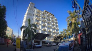 Un hotel de varios pisos con un llamativo letrero 'HOTEL YAKIN', que presenta un diseño arquitectónico moderno con balcones y una entrada cubierta.