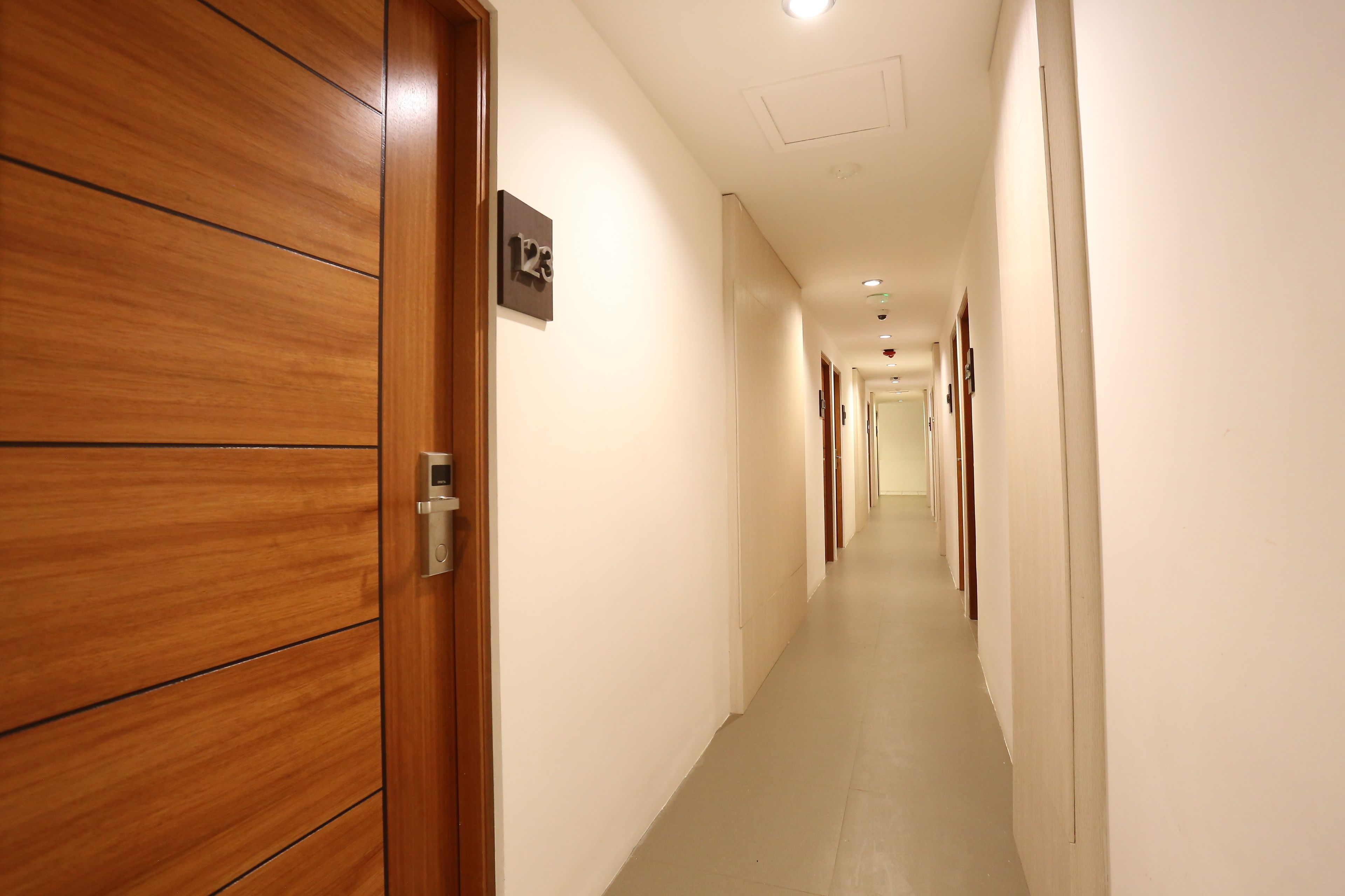 A hallway with wooden doors and a sign indicating room number 123.
