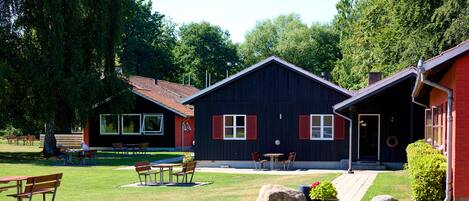 A building with a dark exterior, red shutters, and a paved patio area with outdoor seating.