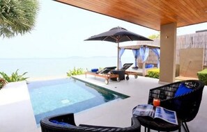 A poolside area with lounge chairs and an umbrella, overlooking a clear body of water. - Tides Boutique Samui Resort & Spa (Koh Samui)