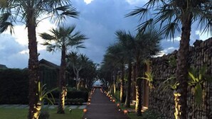 A pathway lined with palm trees and lit lanterns, leading to a building. - Tides Boutique Samui Resort & Spa (Koh Samui)