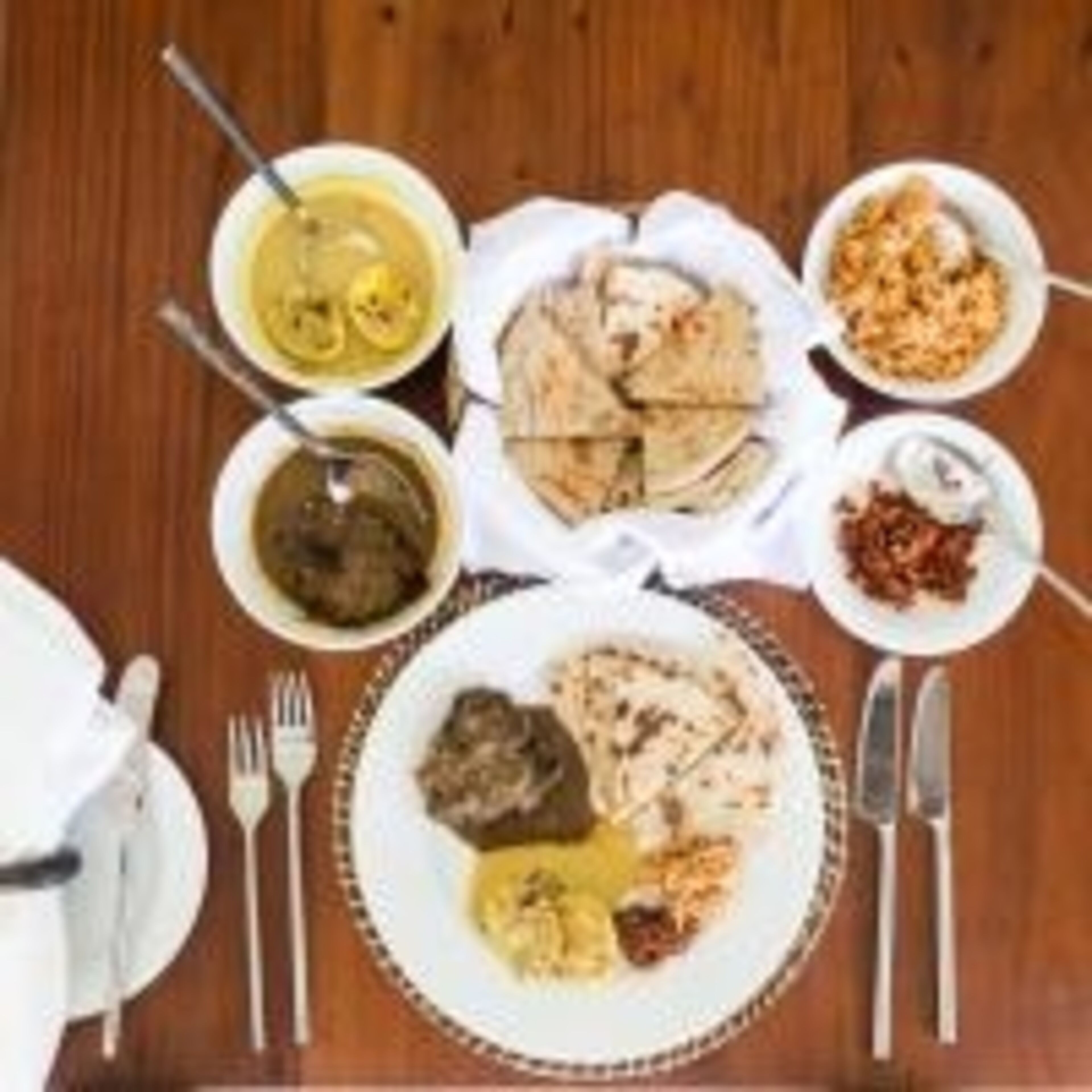 A table with various dishes including a bowl of soup, a plate of flatbread, and a bowl of rice.