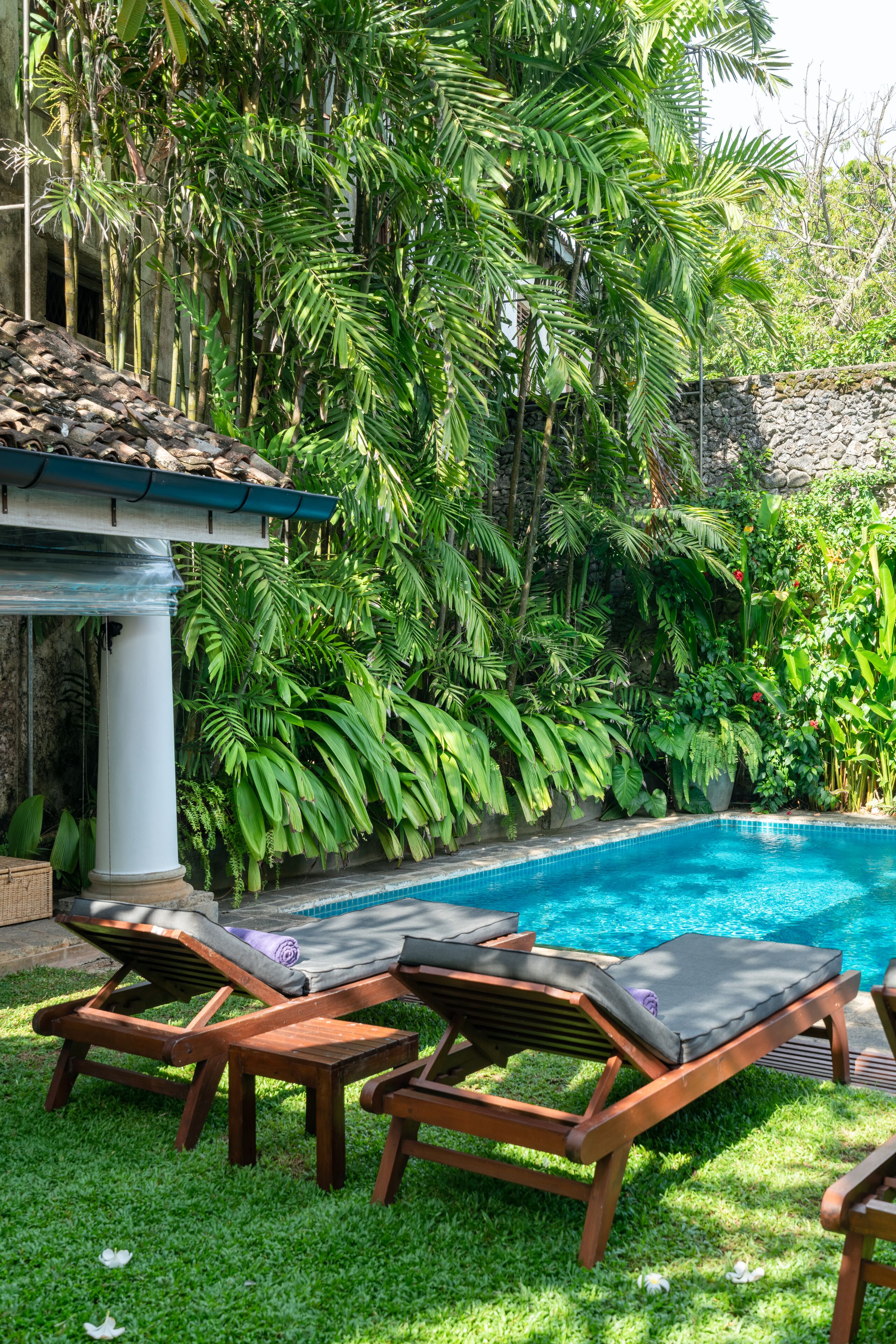 A poolside area with lounge chairs and a stone wall.