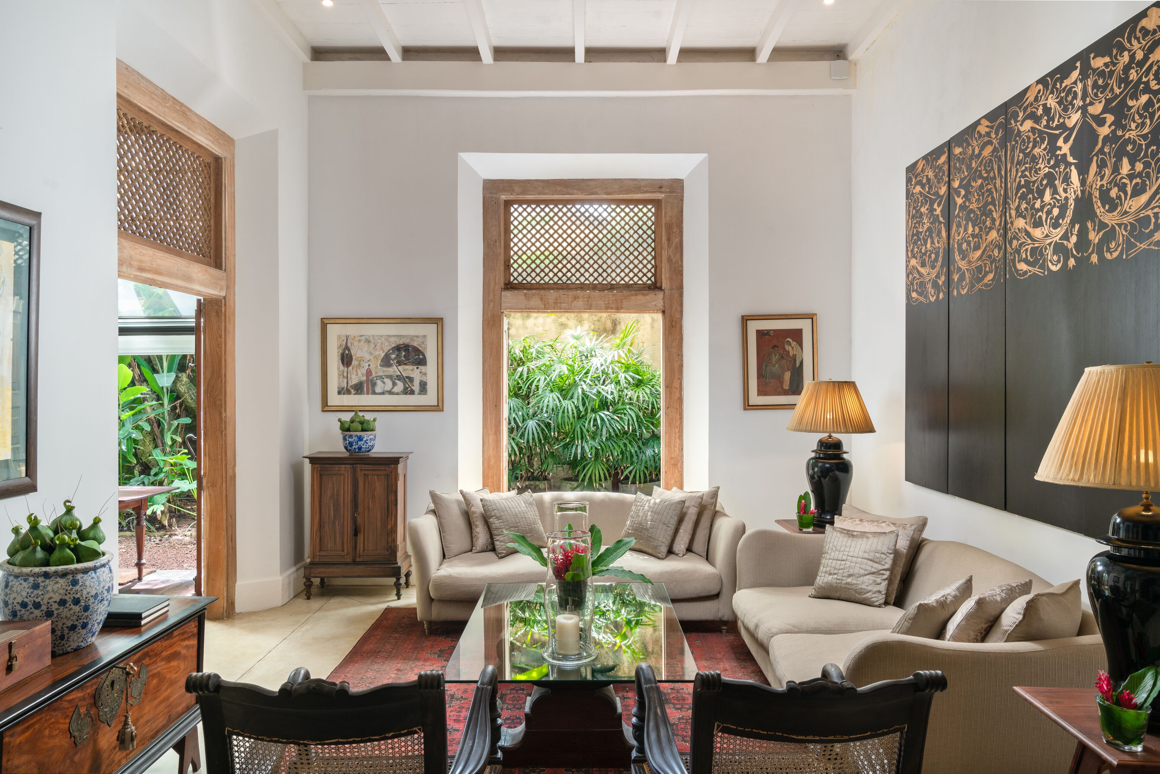 Amplia sala de estar con un sofá grande, una mesa de centro de vidrio y vista a la vegetación a través de una ventana.