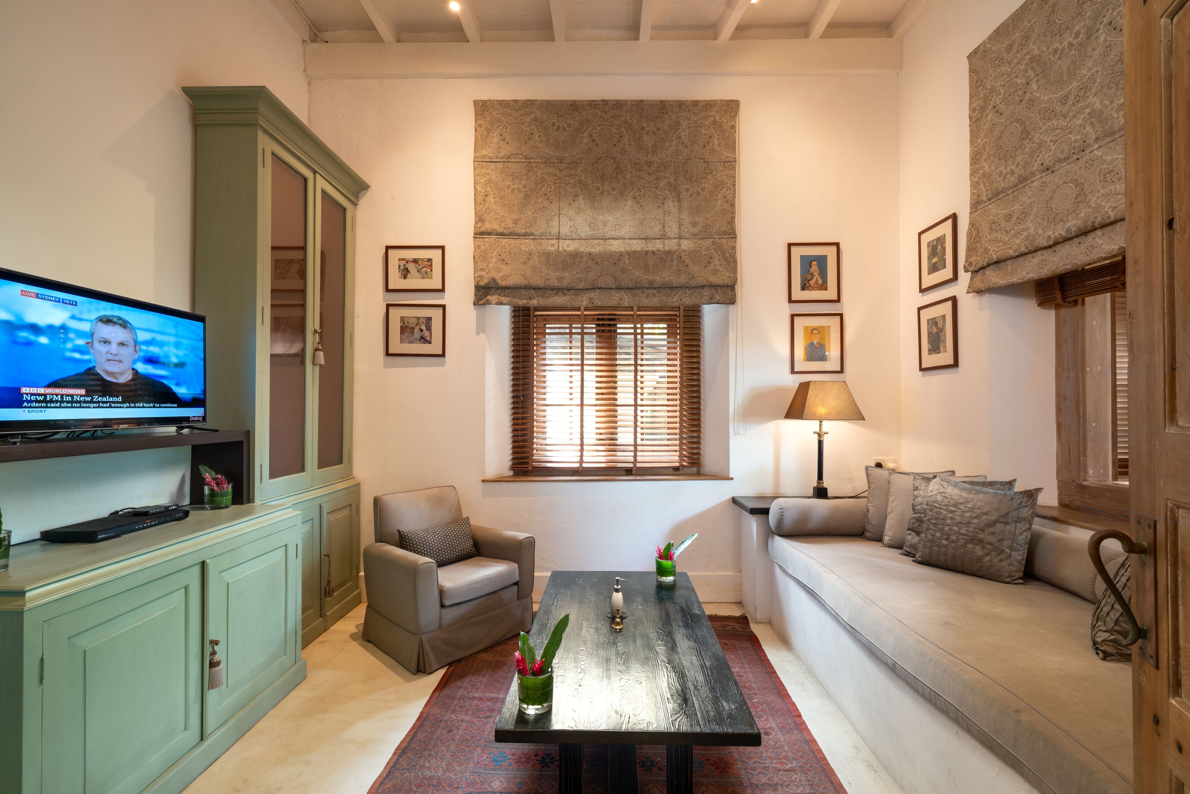 Una sala de estar con televisor, sofá, sillón y una mesa de centro con adornos.