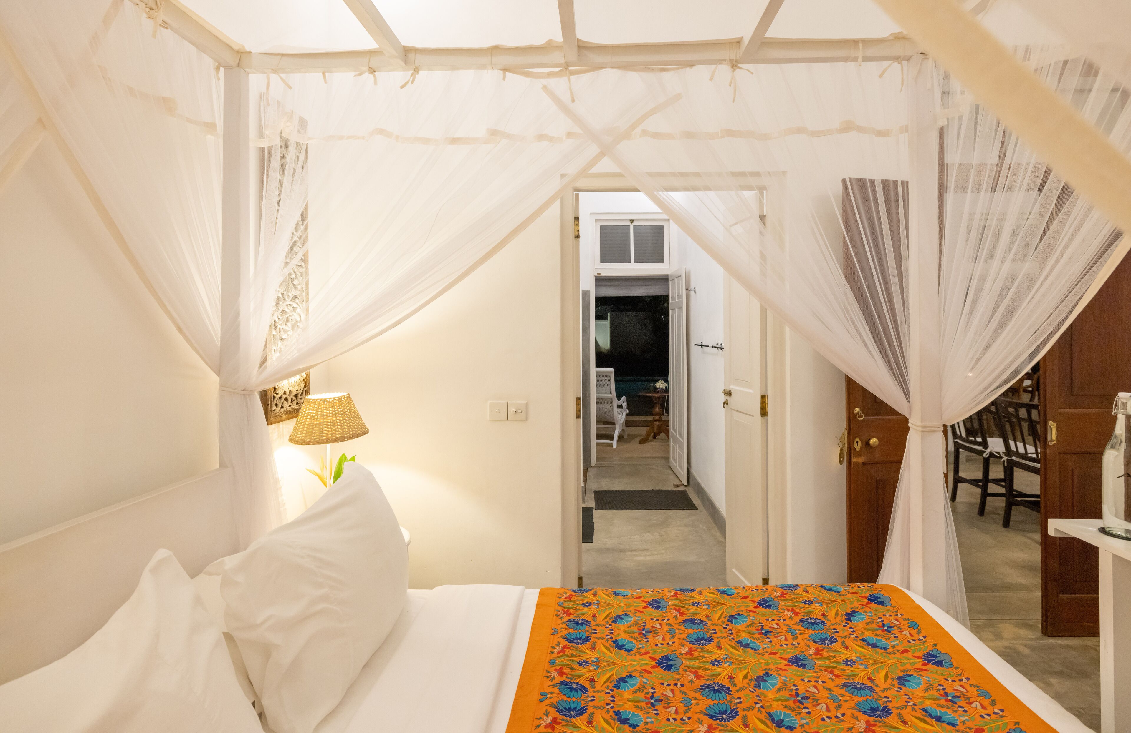 A bedroom with a bed, a nightstand, a lamp, and a canopy bed.