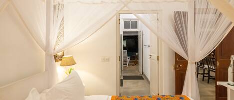 A bedroom with a bed, a nightstand, a lamp, and a canopy bed.