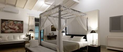 Ein Schlafzimmer mit Himmelbett, Tagesbett, Nachttisch und Lampe.