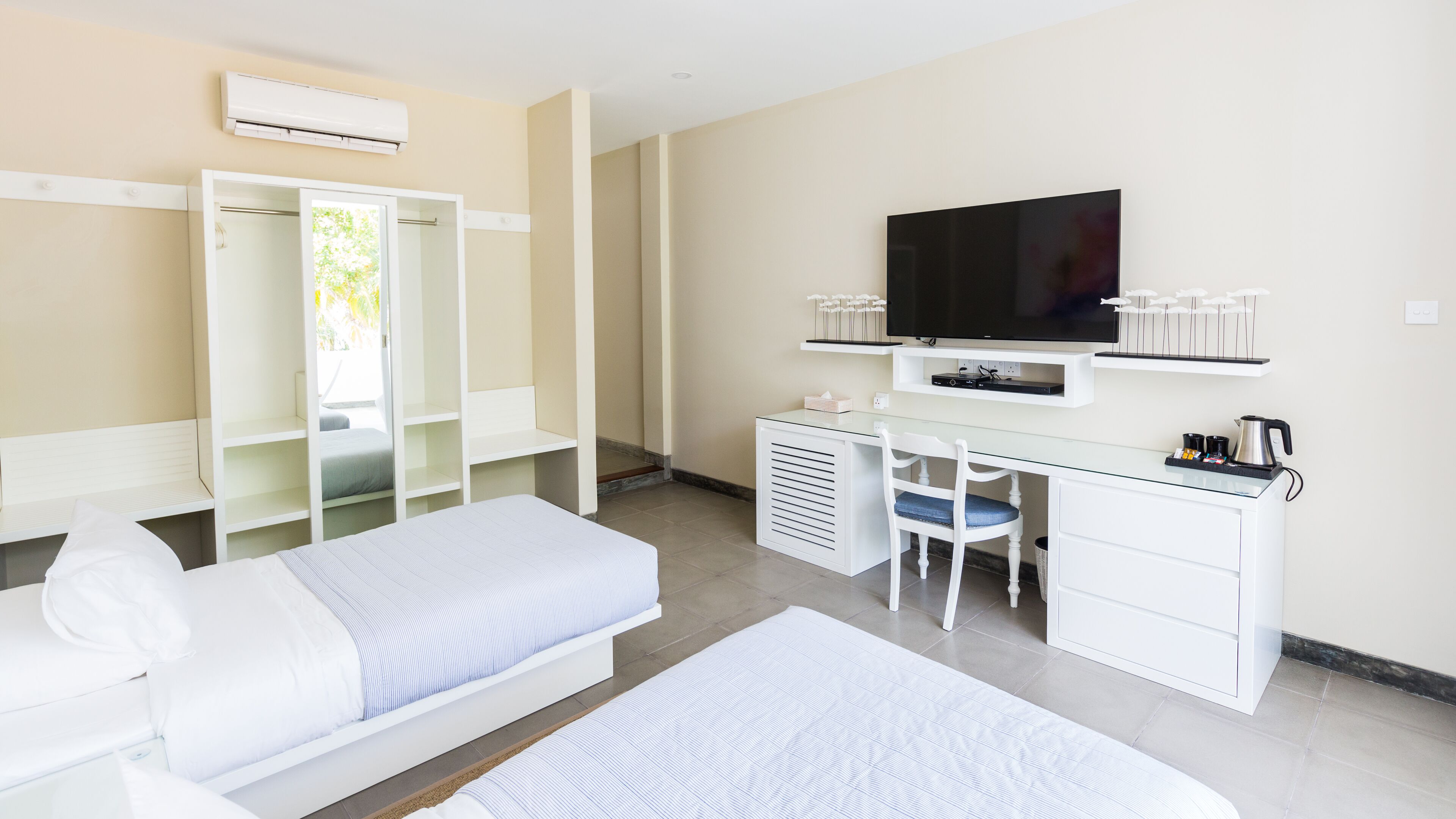Une chambre d’hôtel comprenant un lit, un bureau avec une télévision, une chaise et une armoire.