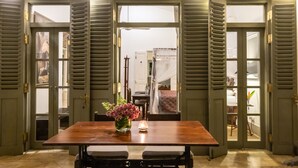 Un coin repas avec une table en bois, deux chaises, un vase de fleurs et une bougie allumée.