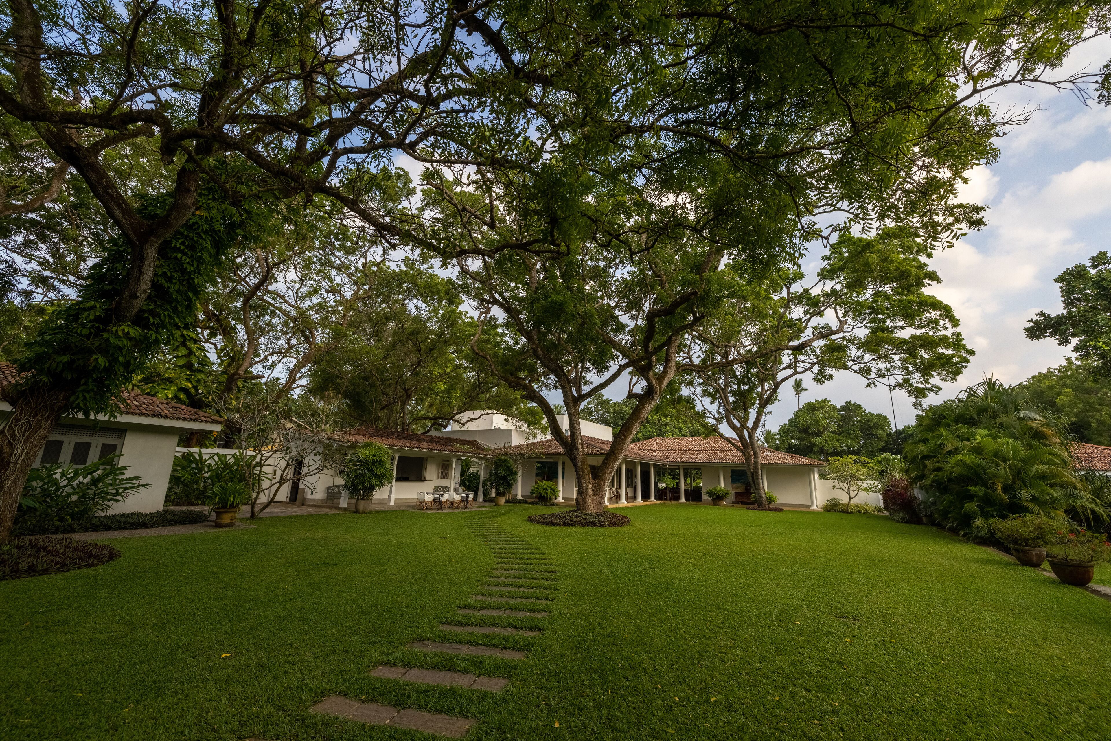 A well-maintained garden with a clear pathway leading to a building with a tiled roof.