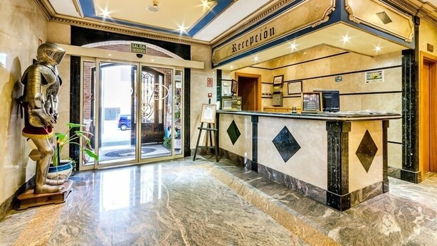 A hotel reception area with a marble floor, a reception desk, and a statue of a knight.