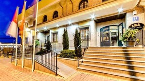 A hotel with a brick facade, a staircase leading to the entrance, and a sign reading "Hotel Carlos I".