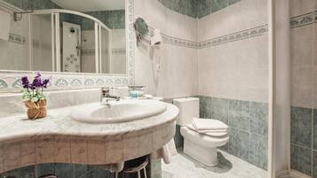 A bathroom with a marble sink, a toilet, and a shower.