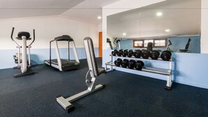 A gym with treadmills, elliptical machines, and a rack of dumbbells.