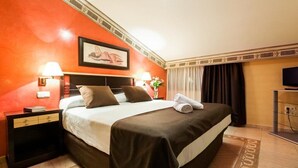 A hotel room with a large bed, two bedside lamps, a flat-screen TV, and a painting on the wall.
