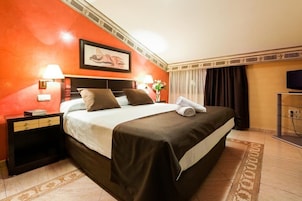 A hotel room with a large bed, two bedside lamps, a flat-screen TV, and a painting on the wall.
