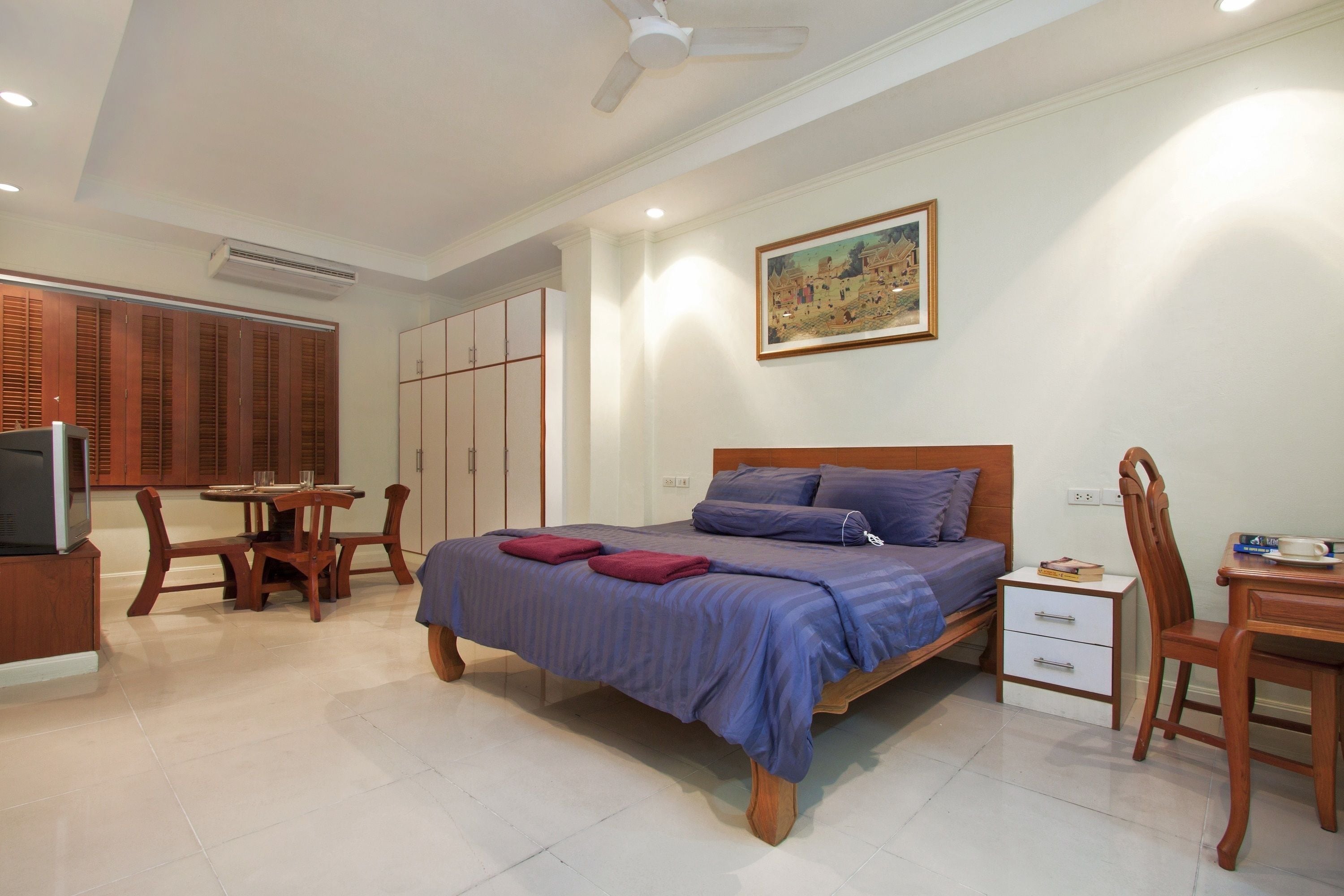 A bedroom with a bed, a desk, a chair, a television, and a wardrobe.