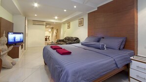 Een slaapkamer met een bed, een televisie, een beeld en een houten hoofdbord.