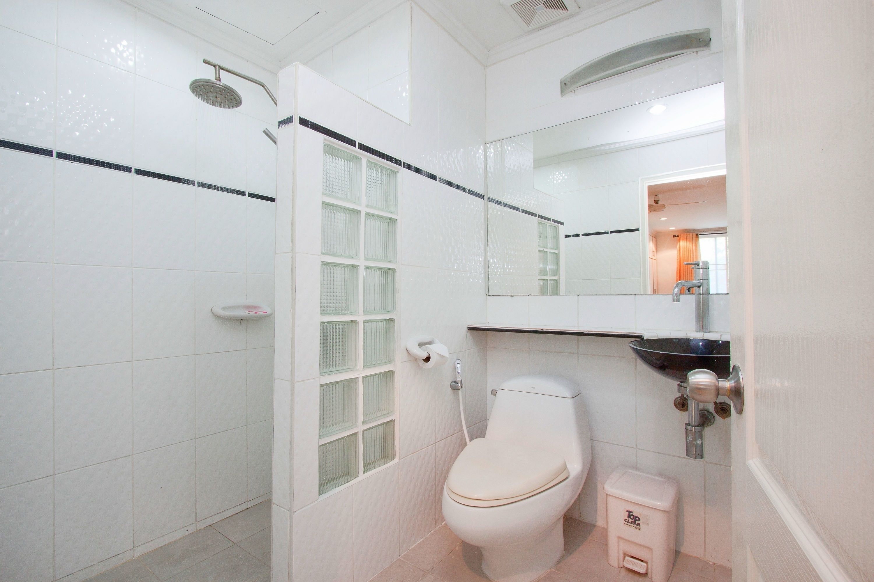 A bathroom with a toilet, a sink, a shower, and a mirror.