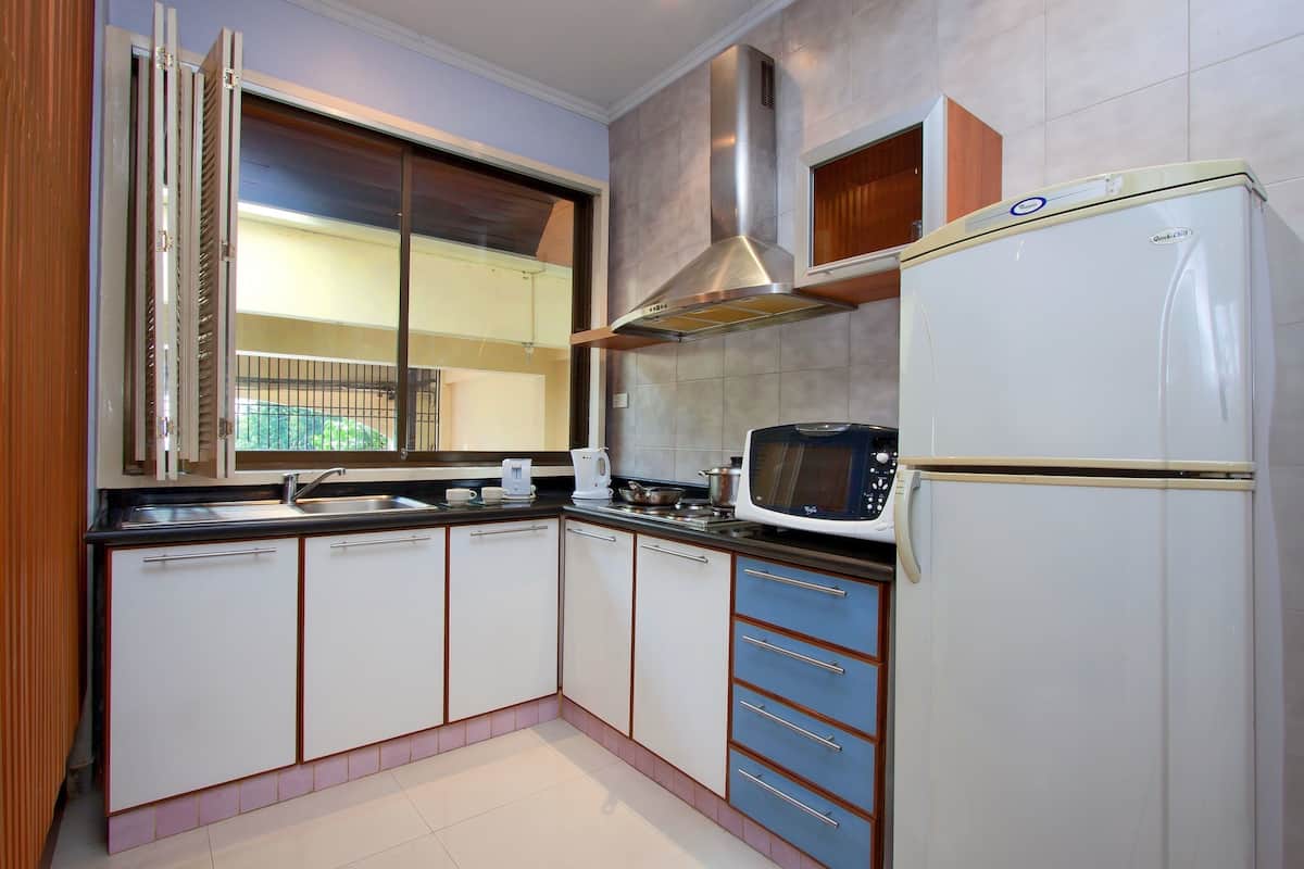 Een keuken met witte kastjes, een magnetron, een fornuis en een koelkast.