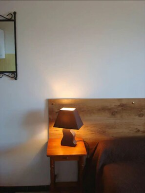 A wooden headboard with a bedside lamp on a small wooden nightstand. - Sole e Monte (Cuttoli-Corticchiato)