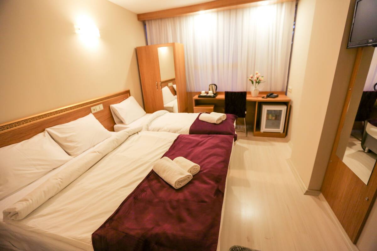 A hotel room with two beds, a desk, a chair, a television, and a mirror.