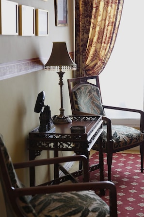 A room with a wooden chair, a table with a lamp, and a decorative statue. - Hotel Villa de Luarca (Valdes)