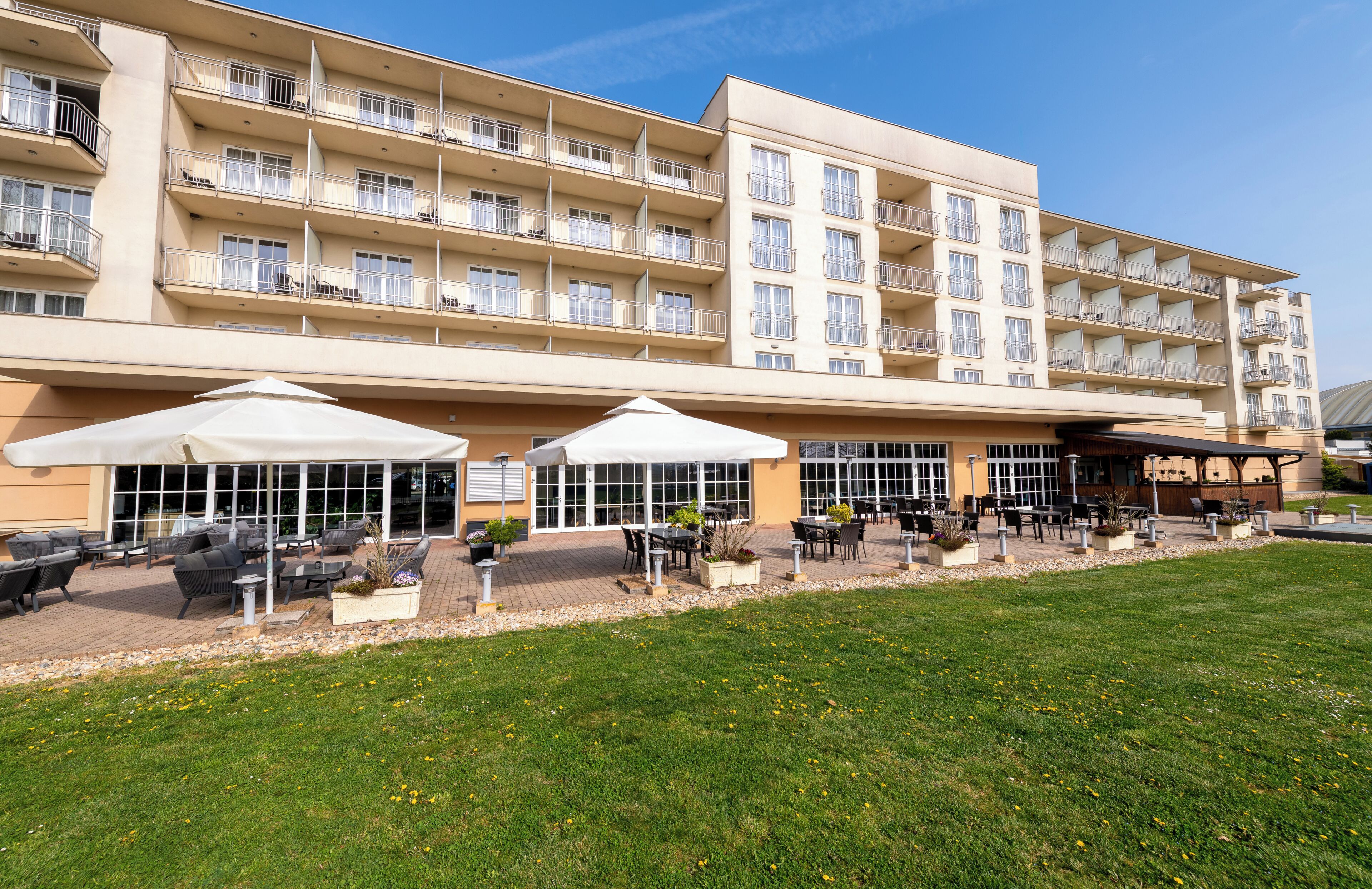 A multi-story hotel with outdoor seating and a grassy area.