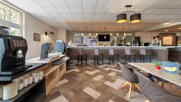 A modern bar area with a coffee machine, seating, and a counter with various bottles.