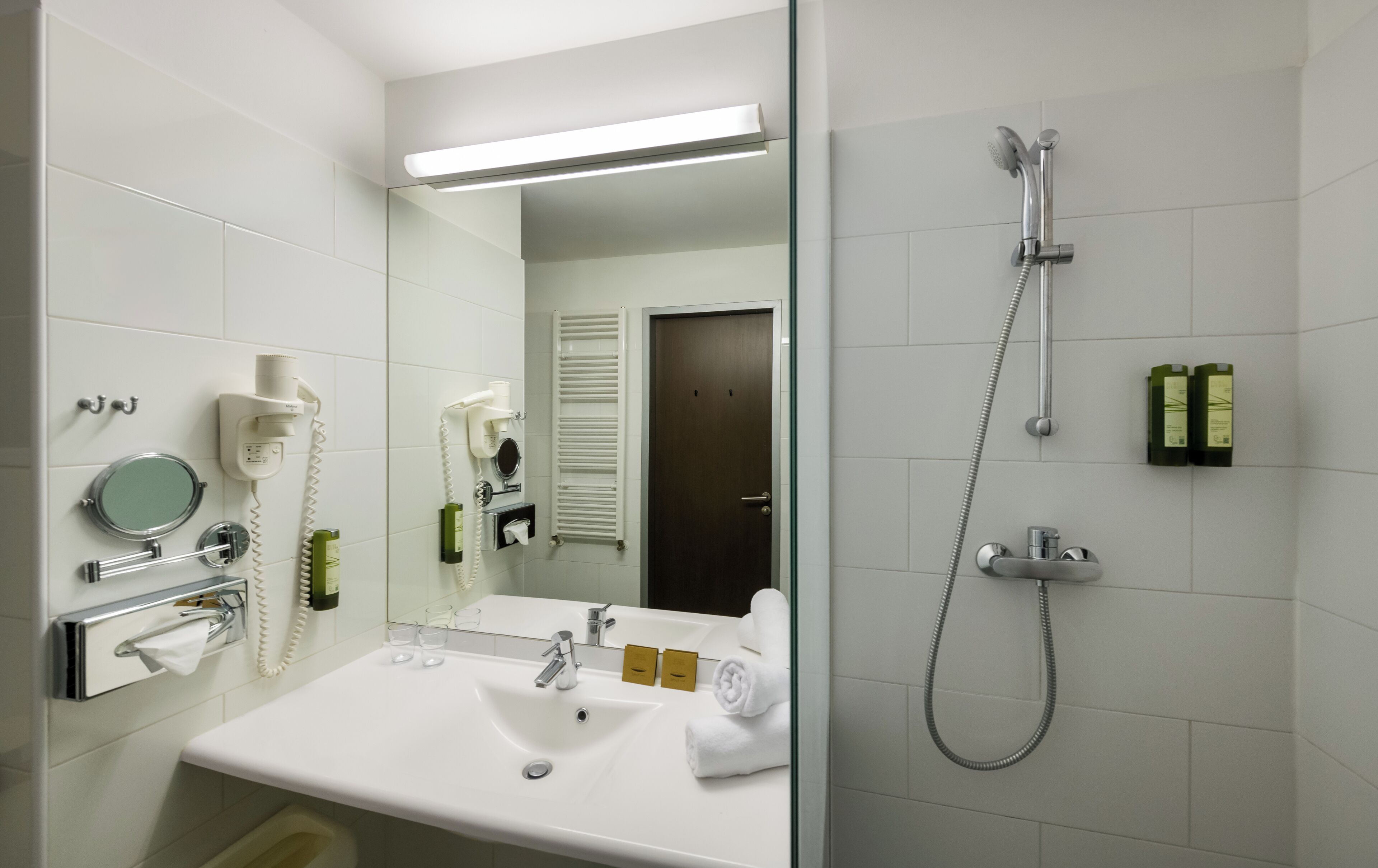 A bathroom with a sink, mirror, towel, and shower.