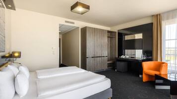 A hotel room with a bed, desk, chair, and a large window.
