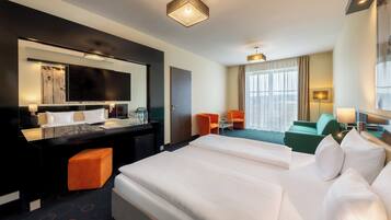 Quarto de hotel com uma cama grande, uma escrivaninha com cadeira, um sofá e uma televisão.